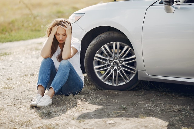 girl sitting by car after accident